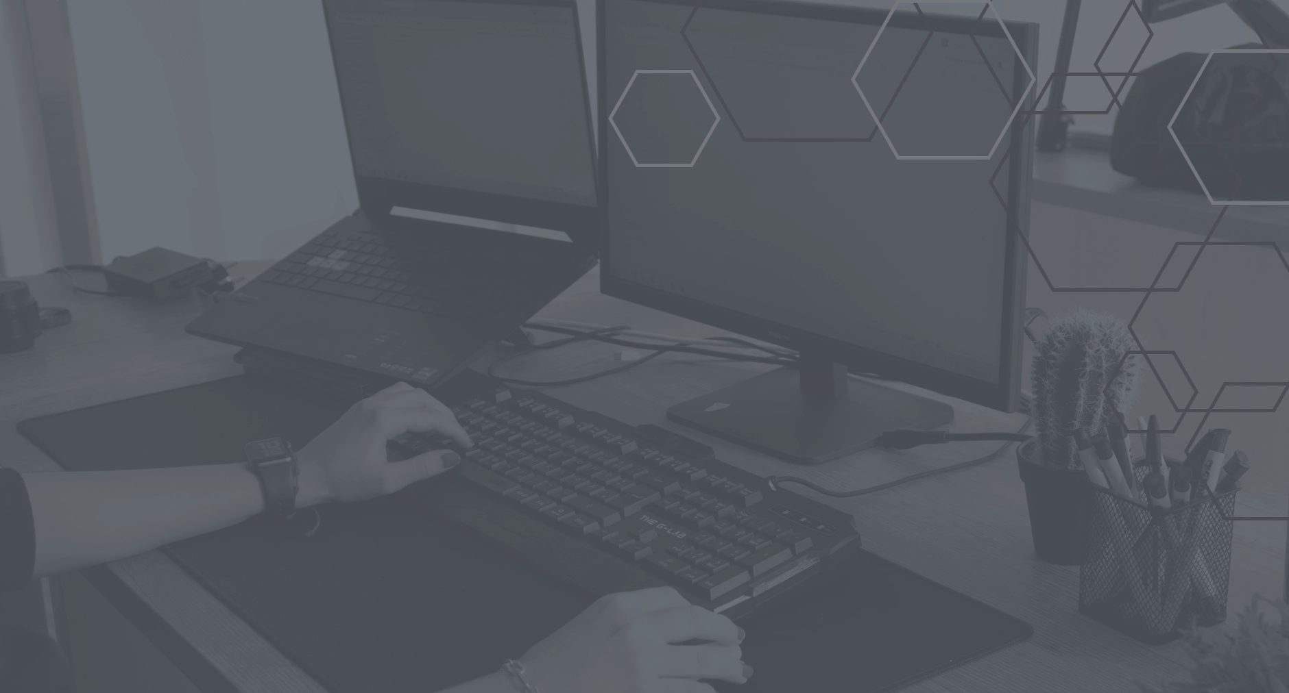 Dark-themed background showing a person working on a dual-monitor computer setup