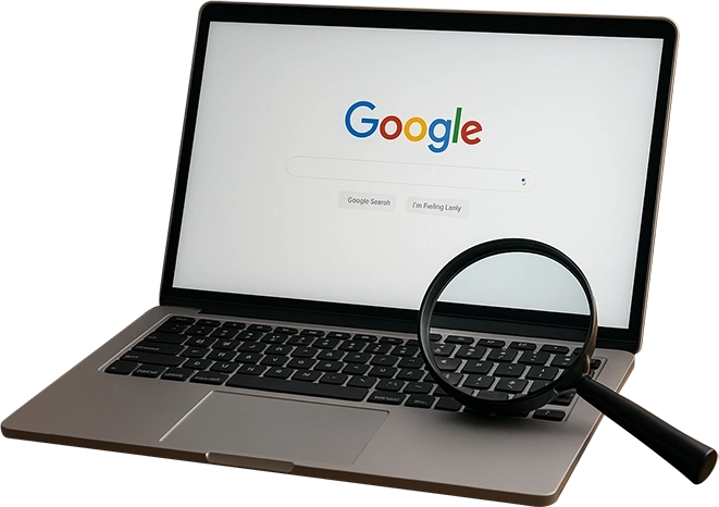 Laptop displaying Google search page with magnifying glass on keyboard